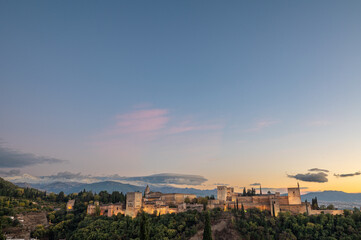 Aerial view of the Alhambra Palace in Granada, Spain with snow-capped Sierra Nevada mountains in the background.