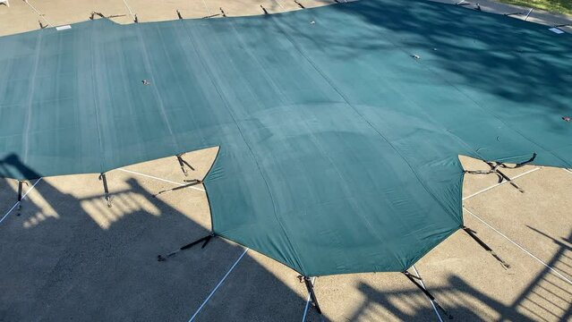 Aerial view swimming pool covered for the winter in suburban neighborhood winterized