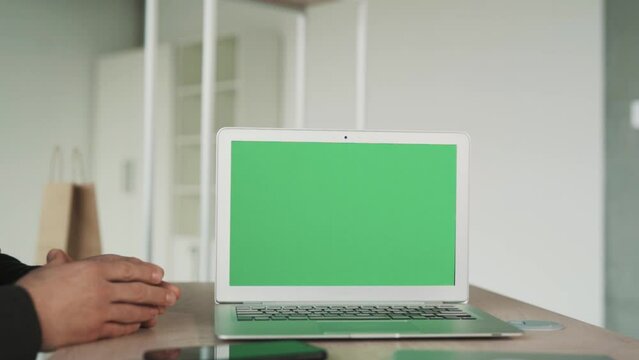 close-up of a laptop screen with chroma key, two male hands shaking in the background