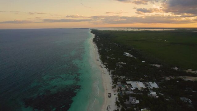 Aerial View Of Sandy Akiin Beach With Turquoise Sea Waves Of The Caribbean And Orange Sunset Sky On Horizon. Dolly Back