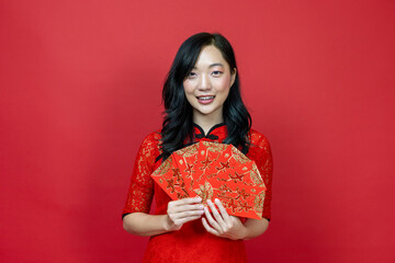 Asian woman holding red money fortune envelope blessing Chinese word which means "May you have great luck and great profitr" isolated on red background for Chinese New Year celebration concept