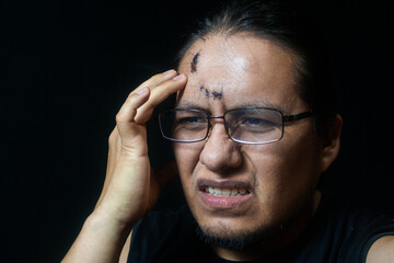 portrait of a latino man with 6 stitches on his forehead, who has headaches