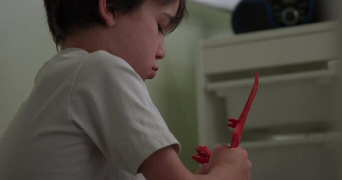 Young Boy Fixing Broken Dragon Action Figure Toy - Side Profile