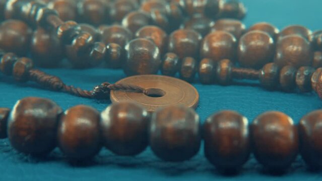 Macro pan shot of a wooden round beads necklace with coin medallion. close up, slow motion, 4K