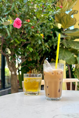 Vietnamese white cold coffee with milk and ice and green tea in terrace of cafe on table outdoors in exotic tropical country
