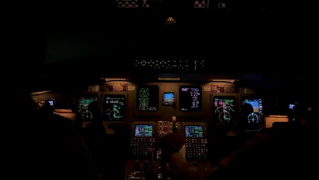 Jet cockpit view in a real flight though stormy clouds with turbulence and lightnings, night light.