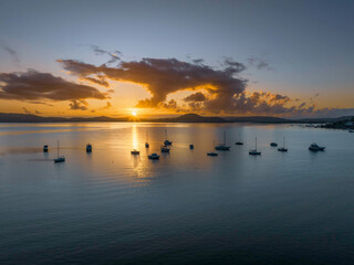Aerial sunrise waterscape with boats, clouds and sun rays
