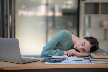 An attractive young businesswoman sleeping on her desk in the office.