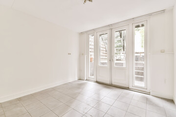 an empty living room with white walls and floor tiles on the floor, there is a sliding glass door...