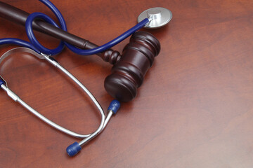 Wooden judge gavel and blue stethoscope on table.