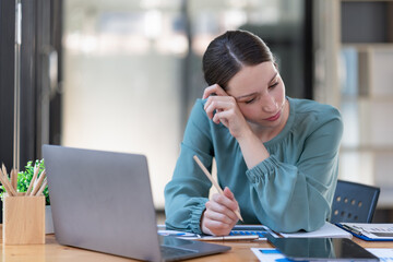 Fototapeta premium Portrait of a female office worker feeling stressed while working in the office room.