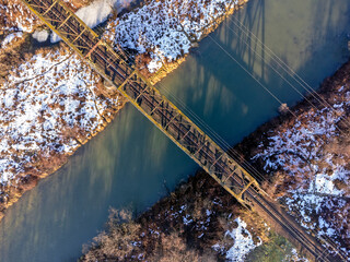 Aerial view. Old railroad bridge. Urban landscape. Winter, river, water, trees, nature, snow. 