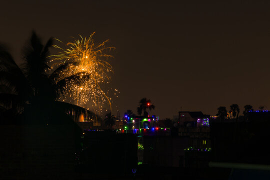 firework during celebration of new year, diwali and other festivals. shot taken against night sky with colorful lights in distant houses. - Powered by Adobe
