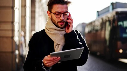 Confident young business man talking on smartphone. Smartphones have become a lifeline for businesspeople on the big city. European businessman talking on the phone walking down the street to work. - Powered by Adobe