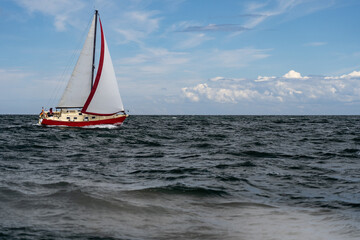 Fototapeta premium Sailboat on blue open sea with clouds on sky. Concept of travel, adventure and vacation.