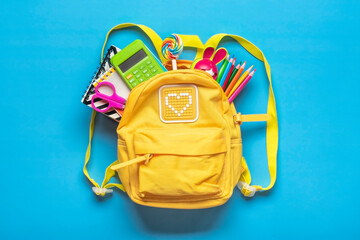 Back to school, education concept Yellow backpack with school supplies - notebook, pens, eraser rainbow, numbers isolated on blue background Top view Copy space Flat lay composition Banner