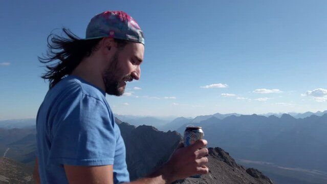 Hiker drinking beer on peak at Rocky Mountain range Close up Kananaskis Alberta British Columbia border Canada