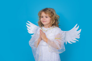 Kid wearing angel costume white dress and feather wings with prayer hands, hope and pray concept. Innocent child.