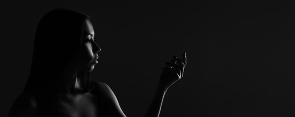Dark female silhouette, hands and face. Artistic portrait. Required photo of the woman's body....