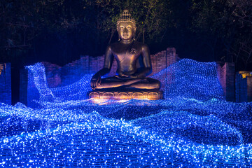 Statue of Buddha with lighting ,Soft focus of Bokeh lights garland or many small lantern festival, colorful lighting bulbs decorated to curtain lamp on dark night, holiday.
