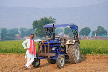 indian farmer standing near tractor at agriculture field. - obrazy, fototapety, plakaty