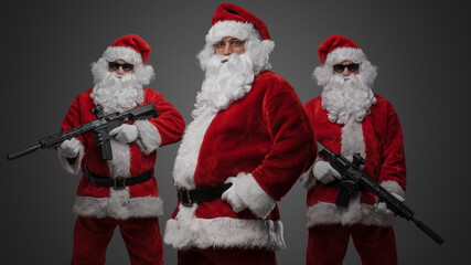 Portrait of isolated on gray background crew of three santa dressed in red costumes.