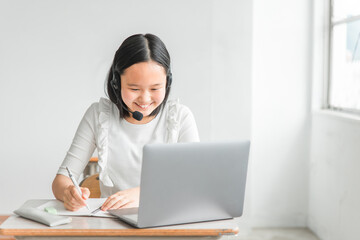 学校の教室・塾でノートパソコンを使って楽しくオンライン学習をする小学生の子供（笑顔・女の子）
