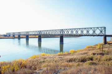 Fototapeta na wymiar Railway bridge over river on sunny autumn day.
