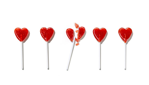 Heart-shaped lollipops among them, one is broken into pieces isolated on white background. Valentine's day. Holiday background