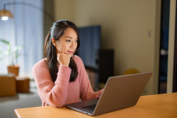 Woman look at the laptop computer at home in the evening