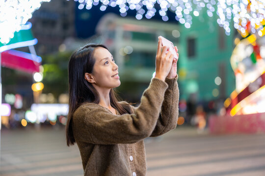 Woman take photo on mobile phone in city at night