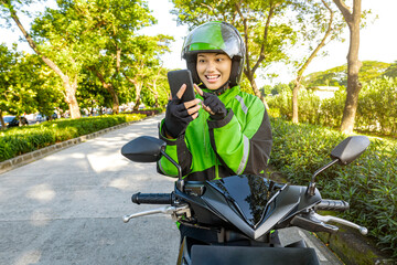 Asian woman works as a motorcycle taxi driver checking order on her mobile phone