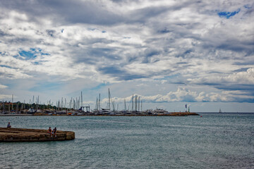 Tourists relaxing at beach S’Arenal of Mallorca Island and swimming in the ocean with mountain panorama in the background on a blue cloudy autumn day. Photo taken October 12th, 2022, Mallorca, Spain.