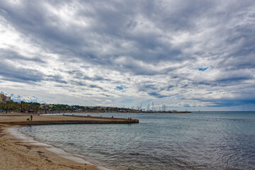 Tourists relaxing at beach S&rsquo;Arenal of Mallorca Island and swimming in the ocean with mountain panorama in the background on a blue cloudy autumn day. Photo taken October 12th, 2022, Mallorca, Spain.