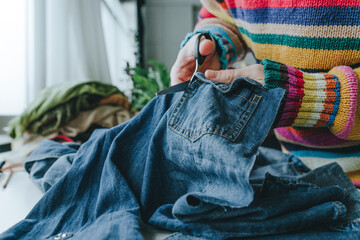 Hands of fashion designer cutting denim jeans