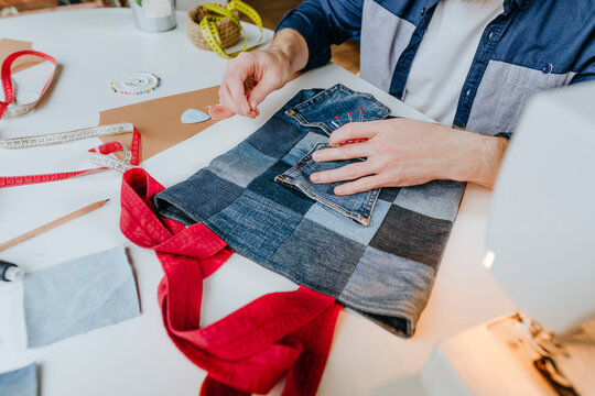 Fashion designer stitching pocket on shopping bag in workshop