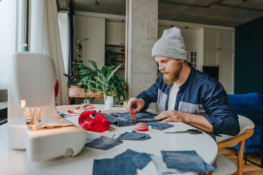 Fashion designer wearing knit hat working on denim bag