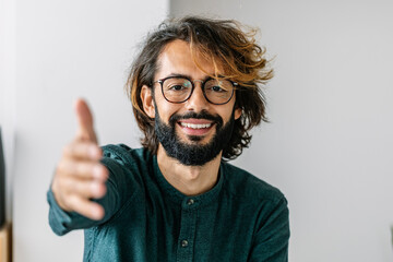 Happy freelancer reaching for handshake at office
