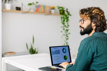 Thoughtful mature freelancer with laptop sitting at desk