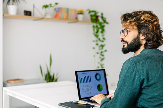 Thoughtful mature freelancer with laptop sitting at desk