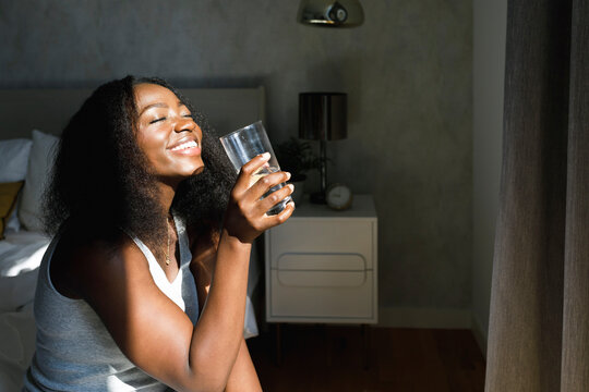 Happy woman holding drinking glass enjoying at home