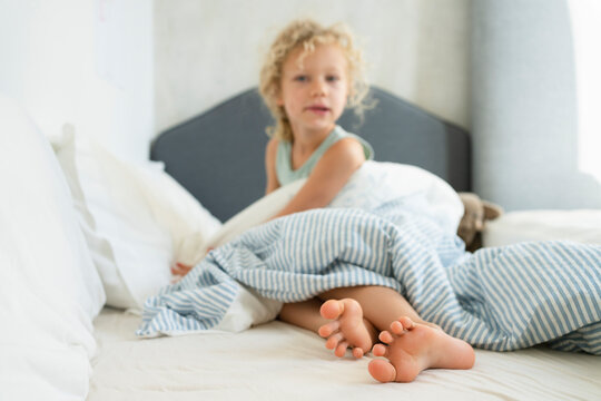 Girl with duvet sitting on bed at home