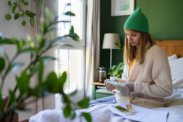 Woman counting currency on bed at home