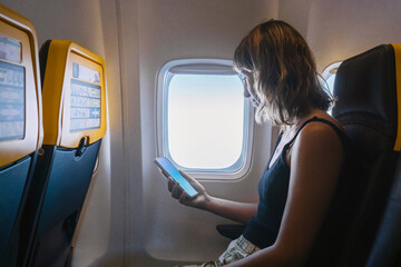 Woman using smart phone in airplane