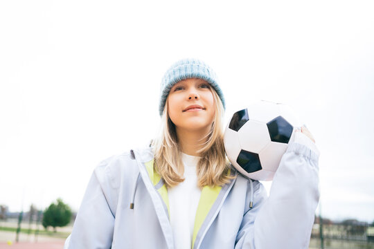 Girl standing with soccer ball under clear sky