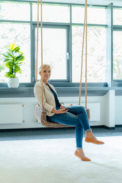 Smiling businesswoman sitting on swig at workplace