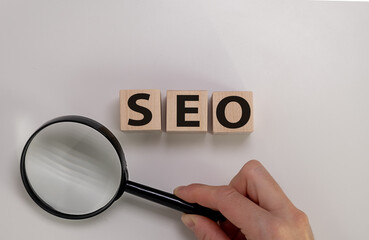 Hand Holding A Magnifying Glass And Looking At The Letters Seo, For Search Engine Optimization