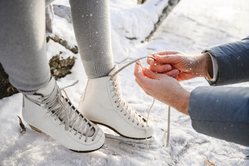 Father tying lace on daughter's ice skates
