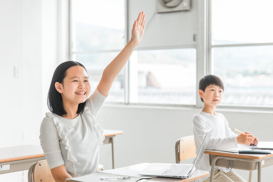 学校・塾のICT教育の授業で挙手するアジア人の子供（小学生・夏期講習・生徒・児童）
