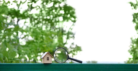 toy house and magnifying glass on green natural abstract background. Symbol of family. Real estate,...